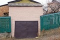 Old brick garage with iron brown gate and green fence