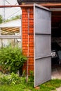 Old brick garage with an open door. There is a ladder propped up against the garage