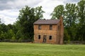 An old brick home building abandon with four opened windows in the middle of a field