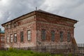 Old brick house behind a wooden sagging fence. Royalty Free Stock Photo