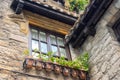 Old brick house in the village. Facade of medieval building with flower pots. Checkered window, roof tiles and exterior decor. Royalty Free Stock Photo