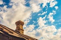 An old brick pipe on the roof of a residential building with an iron roof against a background of clouds, HDR Royalty Free Stock Photo