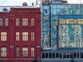 An old brick residential building and an adjoining modern office building with solid glazing reflecting the elements of the street Royalty Free Stock Photo