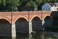 Old brick and stone bridge over small river near old city with ancient houses. Royalty Free Stock Photo