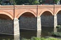 Old brick and stone bridge over small river near old city with ancient houses. Royalty Free Stock Photo