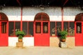 Old brick wall with red doors and windows and two pot plants. Royalty Free Stock Photo