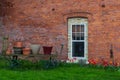 Old brick wall with tulips, green grass and old wagon with pots. Royalty Free Stock Photo