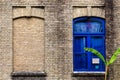 Old brick wall with two windows, one false, other with glass and blue color frame Royalty Free Stock Photo