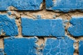 Old brick wall with uneven cement layer painted blue. Close-up. Copy space