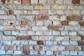 an old brick wall in an uninhabited building. A destroyed house after a tornado or cataclysm. Poor-quality plaster falls off from