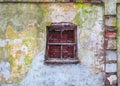 The old brick wall which covered colorful damaged plaster with broken window Royalty Free Stock Photo