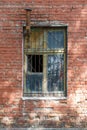 Old brick wall with window. Window has a grate and a chimney Royalty Free Stock Photo