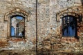 Old brick wall with windows of abandoned building. Grunge background of aged stone surface. Royalty Free Stock Photo