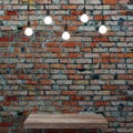 Old brick wall with wooden shelf and glowing light bulbs