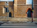 Old brick wall, a worn urban street with crosswalk, a concrete sidewalk and traffic light in a old european city Royalty Free Stock Photo