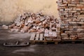 a lot of old bricks stacked on a pallet near the wall of the building Royalty Free Stock Photo