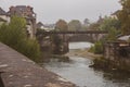 Old bridge over the river on rainy day. Cloudy day in medieval village in France. Arched bridge over canal. Autumn landmark. Royalty Free Stock Photo