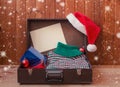 Old briefcase with christmas presents and woolen sweater, fluffy Santa hat and empty card for your text Royalty Free Stock Photo