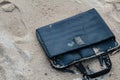 Old briefcase on the sand with footprints. Royalty Free Stock Photo