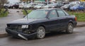 Old broken abandoned dark gray car in the yard of an apartment building