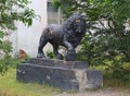 An old broken abandoned lion statue in the roadside bushes