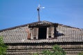 old broken attic window of a house with a rooftop antenna