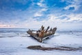 Old broken boat wreck and rocky beach in wintertime. Frozen sea, evening light and icy weather on shore like fairy tale country. Royalty Free Stock Photo
