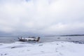 Old broken boat wreck and rocky beach in wintertime. Frozen sea, evening light and icy weather on shore like fairy tale country Royalty Free Stock Photo