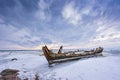 Old broken boat wreck and rocky beach in wintertime. Frozen sea, evening light and icy weather on shore like fairy tale country. Royalty Free Stock Photo