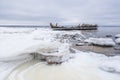 Old broken boat wreck and rocky beach in wintertime. Royalty Free Stock Photo