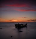 Old broken boat wreck on the shore, a frozen sea and beautiful blue sunset background. Royalty Free Stock Photo