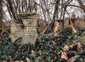 An old broken cross shaped tombstone in a very old abandoned cemetery.