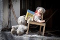 Old broken doll, children`s book, dusty bear, wooden chair on the window of an abandoned kindergarten in ghost town Pripyat,