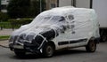 An old broken down car is wrapped in plastic wrap