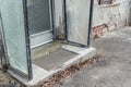 Old broken entrance area of a front door with glass walls and glass roofing, Germany