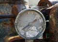 Old broken gauge with traces of numbers on the dial on a large old rusty engine