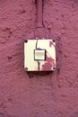 Old broken light switch on red wall