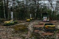 Old broken rusty metal radioactive yellow cars, children`s electric cars, abandoned among vegetation, the park of culture and rec