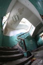 Old broken staircase with turquoise tiles, stone stairs and metal railing with wooden handrail. Several floors house.