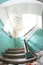 Old broken staircase with turquoise tiles, stone stairs and metal railing with wooden handrail. Several floors house. Royalty Free Stock Photo