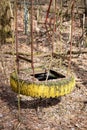 Old broken swing made of metal and car tire on abandoned playground among trees in ghost town Pripyat, Chernobyl Exclusion Zone Royalty Free Stock Photo