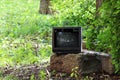 old broken television stands on a concrete pedestal in the city yard.