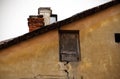 Old broken tiny wooden brown door near the roof top of aged old town building