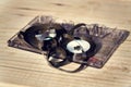 Old broken unwound compact cassette audio tape messed up on wooden background Royalty Free Stock Photo