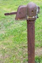 An old, broken village column. Water supply device. Iron, rusty, covered with moss. Vertical, close-up on a background of green Royalty Free Stock Photo