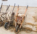 Old and broken wheelbarrows placed against the wall in a row outside Royalty Free Stock Photo