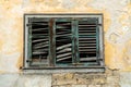 Old broken window shutters on a dilapidated and run down house front with chipped paint and plaster Royalty Free Stock Photo