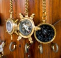 Old bronze compasses are hanging on a chain on a wooden wall