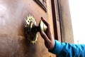 Old bronze door handle pushed by mans hand