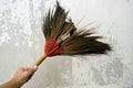 A old broom with handle in hand on grunge wall background Royalty Free Stock Photo